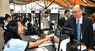Mr Chan (right) visited the shuttle bus ticket counter in the departure hall of the Passenger Clearance Building at the Hong Kong Port of the Hong Kong-Zhuhai-Macao Bridge.