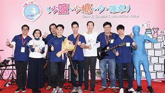 醫生組成的樂隊（St John Band）在演唱「不再油鹽」和「糖份過高」後與降低食物中鹽和糖委員會主席陳智思先生(右四)和食物及衞生局局長陳肇始教授(左二)台上合照。