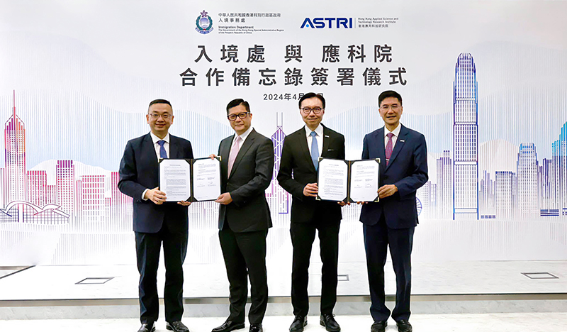 在鄧局長（左二）和香港應用科技研究院（應科院）董事局主席李惠光先生（右二）見證下，入境事務處處長郭俊峯先生（左一）和應科院行政總裁葉成輝博士（右一）在二零二四年四月三十日簽署合作備忘錄，以推動公共服務的創新科技方案。 